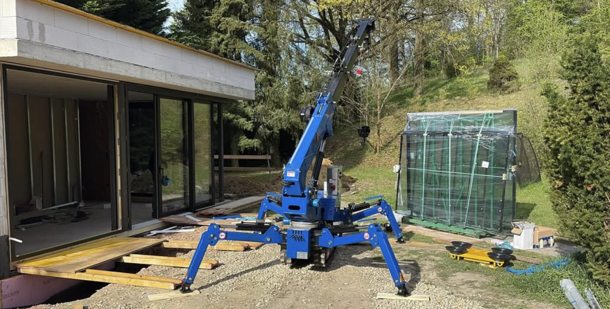 Blauer Spinnenkran hebt ein großes Glaselement