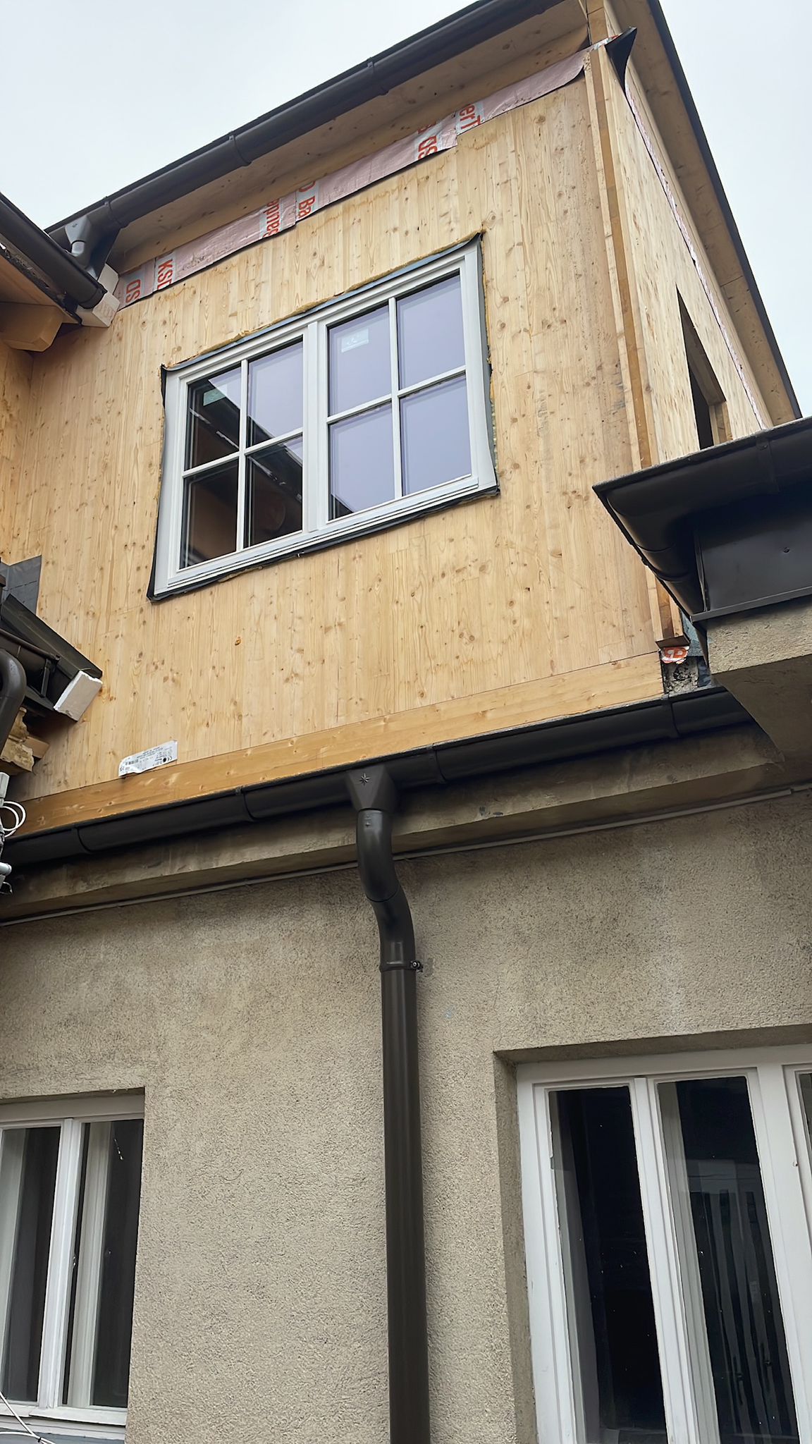Neues weißes Sprossenfenster in einer Holzfassade